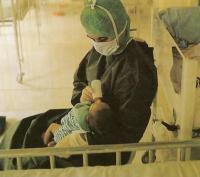 Ребенка с врожденной недостаточностью в стерильных условиях кормит медсестра